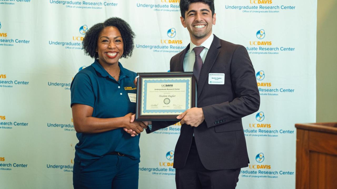 Dark haired male student receiving award
