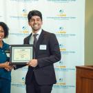 Dark haired male student receiving award